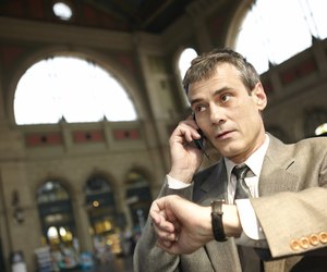 Businessman on cell phone and checking watch