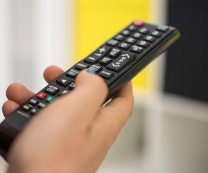 Close up of a hand holding a television remote control.