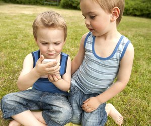 Twin brothers looking at cell phone in park