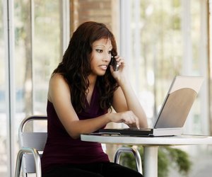 Woman talking on cell phone with laptop