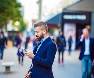 Manager with smartphone listening music outside in the street