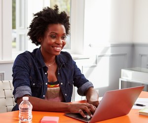 Young black woman using laptop computer at a desk, close-up