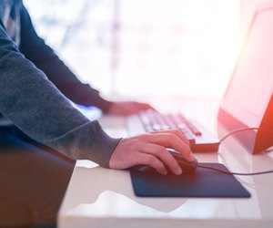 Male hand holding computer mouse with laptop keyboard