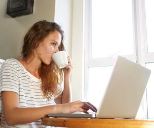 Young woman working on laptop and drinking coffee