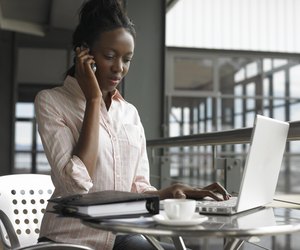 Young businesswoman sitting using laptop and mobile phone