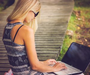 Young, beautiful woman resting in the park and using laptop.