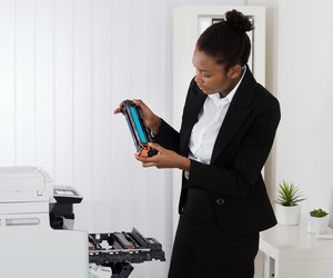 Businesswoman Fixing Cartridge In Office
