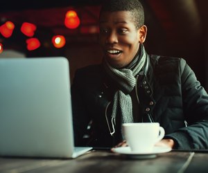 Indoor portrait of young black man sitting in cafe, drinking