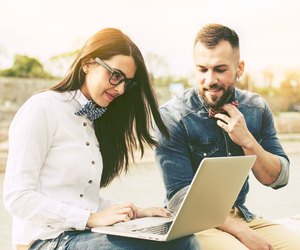 Couple of hipster friends using laptop in the city