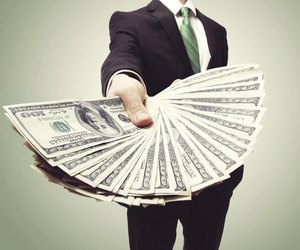 Business Man Displaying a Spread of Cash