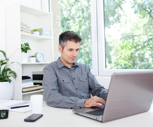 Young man at office desk, working on laptop
