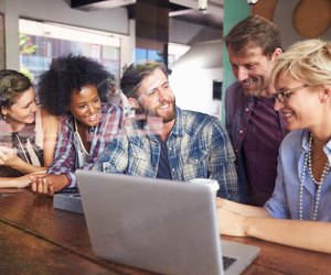 Group Of Businesspeople Working On Laptop In Coffee Shop