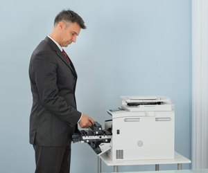 Businessman Fixing Cartridge In Printer Machine At Office