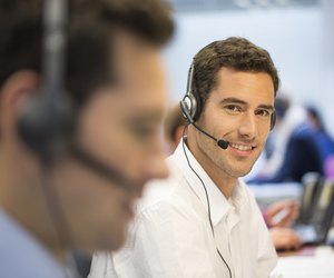 Businessman at office on the phone with headset, looking camera