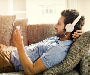 Man on couch watches a movie on mobile phone