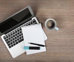 Blank notepad over laptop and coffee cup