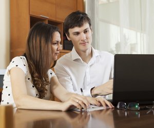 Young couple looking financial documents in laptop