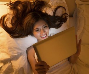 Young woman using some application on her digital tablet at night, view from above