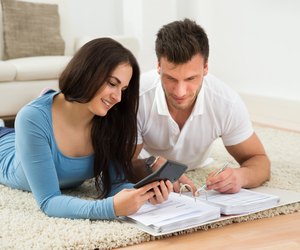 Happy Young Couple Calculating Invoice