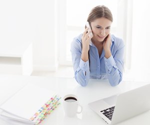 Woman using cell phone and looking at computer