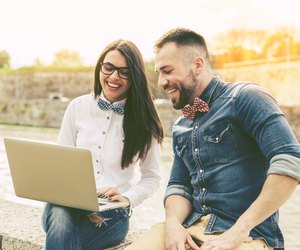 Couple of hipster friends using laptop in the city