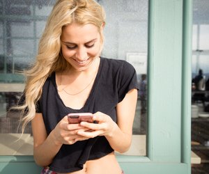 Pretty young woman sends a text message from her phone.