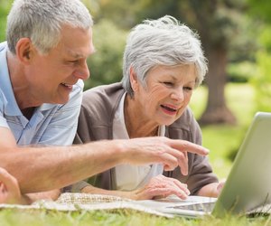 Smiling senior couple using laptop at park