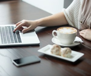 Close-up of female hands working on laptop in cafe