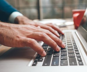 Opened laptop and male hands typing