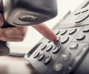 Closeup of male hand holding telephone receiver while dialing a