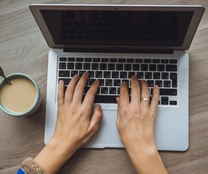 Laptop and coffee cup in girl's hands