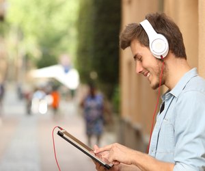 Man using a tablet with headphones on the street