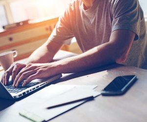 Man with mobile phone and laptop in working in office