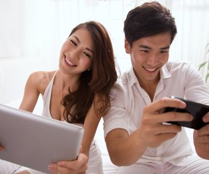 Young couple holding mobile phone and tablet computor on bed