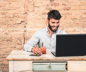 Young hipster guy sitting at vintage desk with laptop