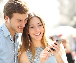 Couple sharing music from a smart phone on the street