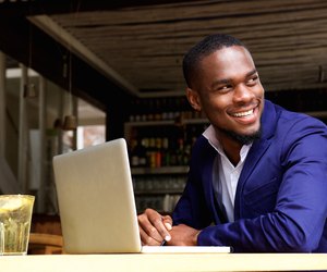 Smiling black businessman with laptop at cafe