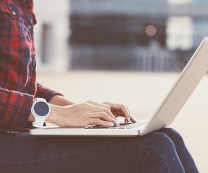 Girl wearing smartwatch using laptop outdoors