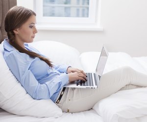 Close-up view of Woman using laptop on her bed
