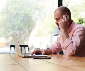 Business man talking on smart phone and look to laptop