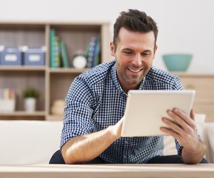Smiling handsome man using digital tablet at home