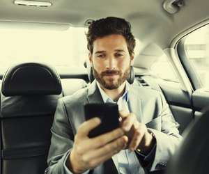 Hipster man in car Typing text message on mobile phone