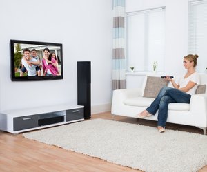 Woman Watching Television While Sitting On Sofa
