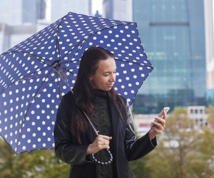 Young woman talking on the phone with umbrella in hand