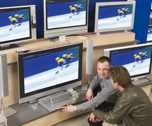 Salesman demonstrating television to male customer in shop
