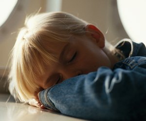 Girl (4-7) resting on table, close-up