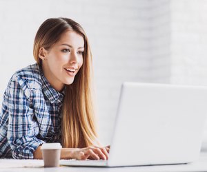 Happy student girl using laptop at home