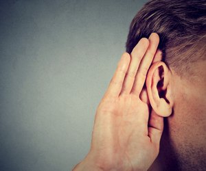 man holds hand near ear and listens carefully