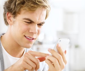Frustrated man sending text message using mobile phone