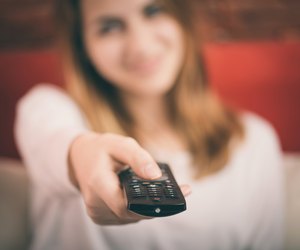Smart tv and hand pressing remote control.